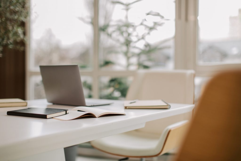 Heller Arbeitsplatz mit Laptop, Pflanzen und stilvoller Einrichtung im Steuerbüro